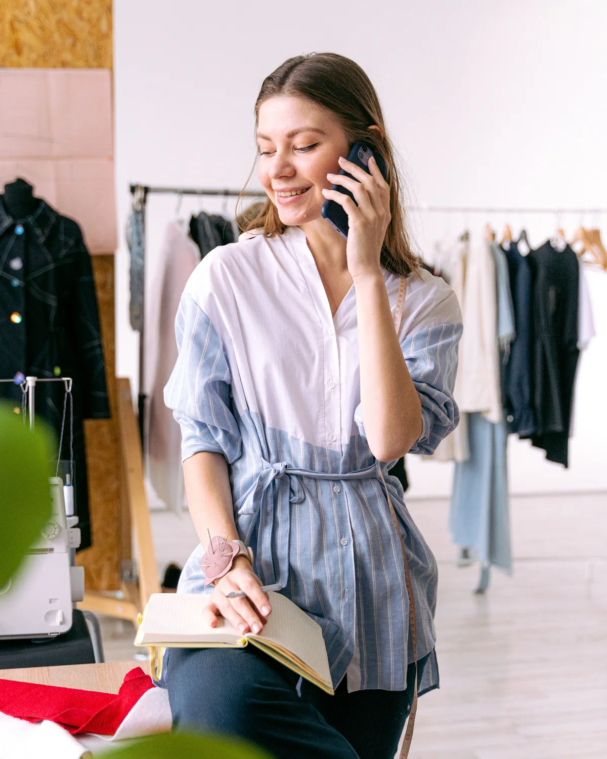 Una comerciante sonríe mientras atiende el teléfono en su taller de ropa